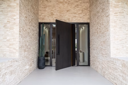 Oversized pivot exterior wood door creating a dramatic architectural entrance